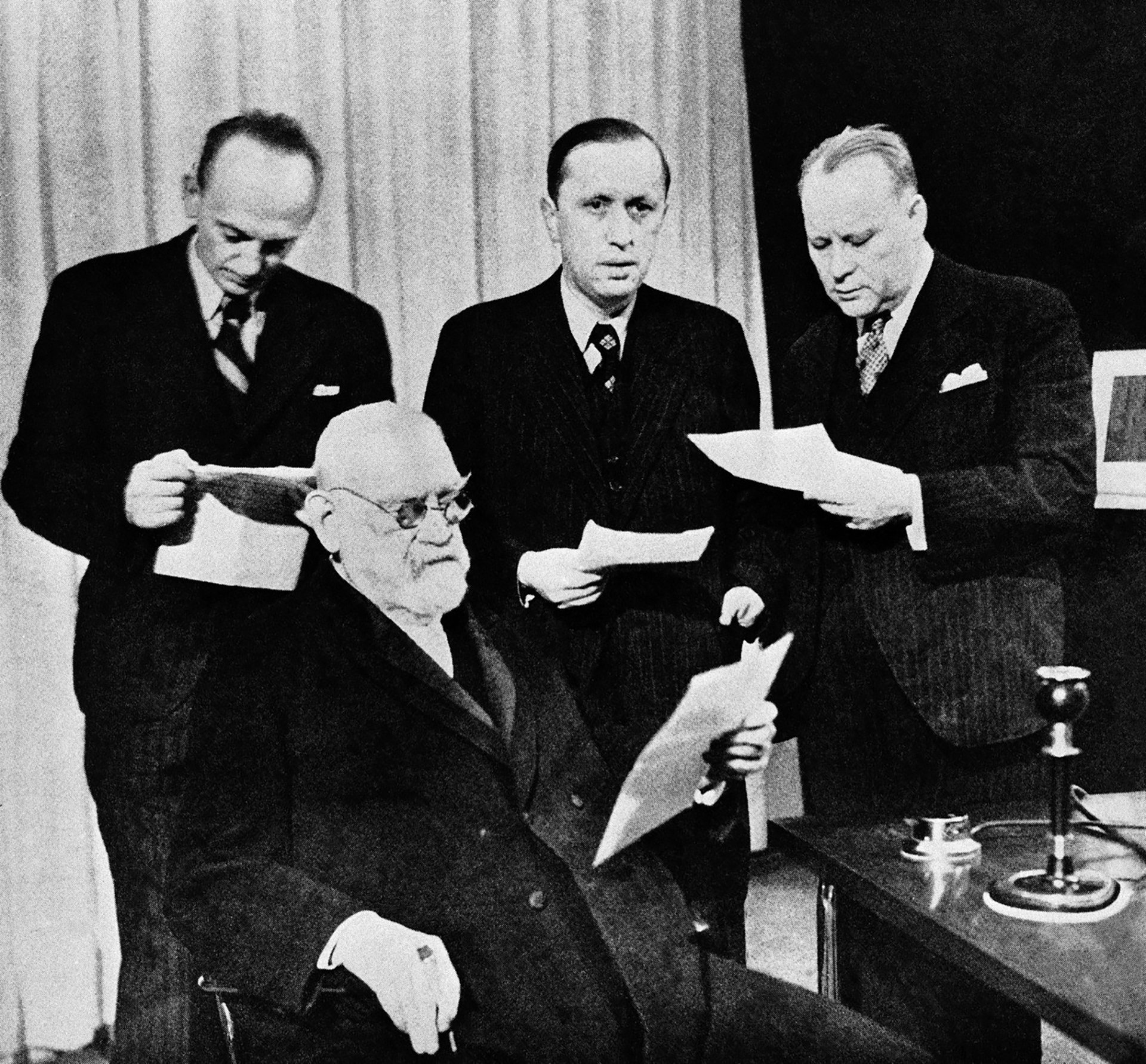Československé rozhlasové stanice vysílaly na Štědrý den roku 1937 poselství míru celému světu. (Sedící František Křižík, nad ním uprostřed Karel Čapek)